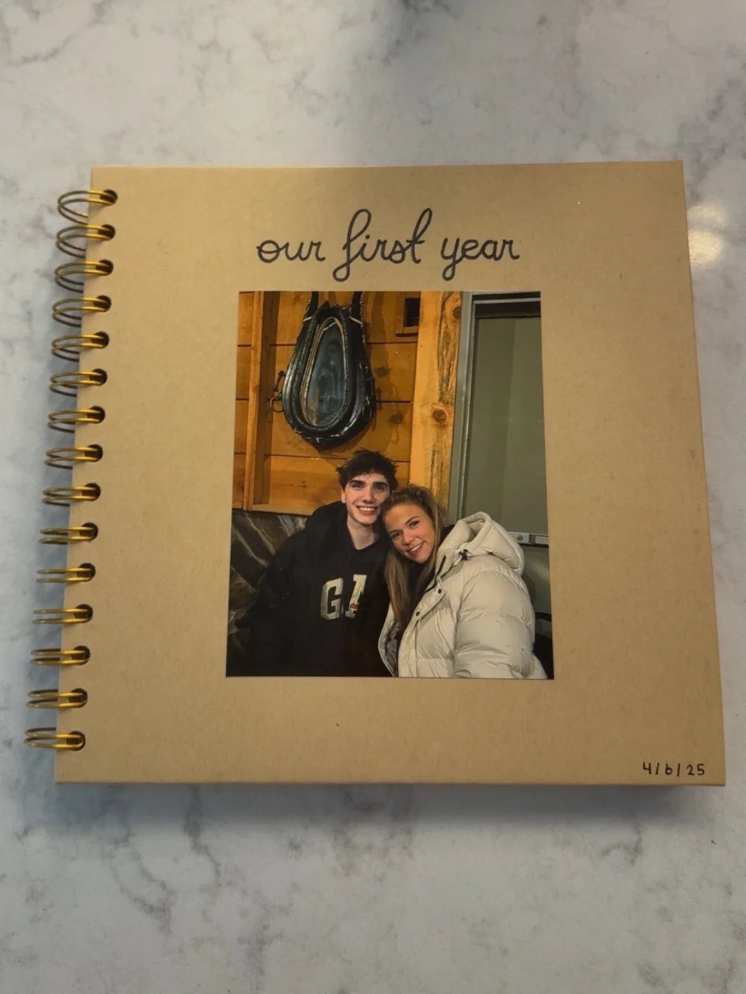 Brown spiral scrapbook cover with a couple's photo and 'our first year' text.