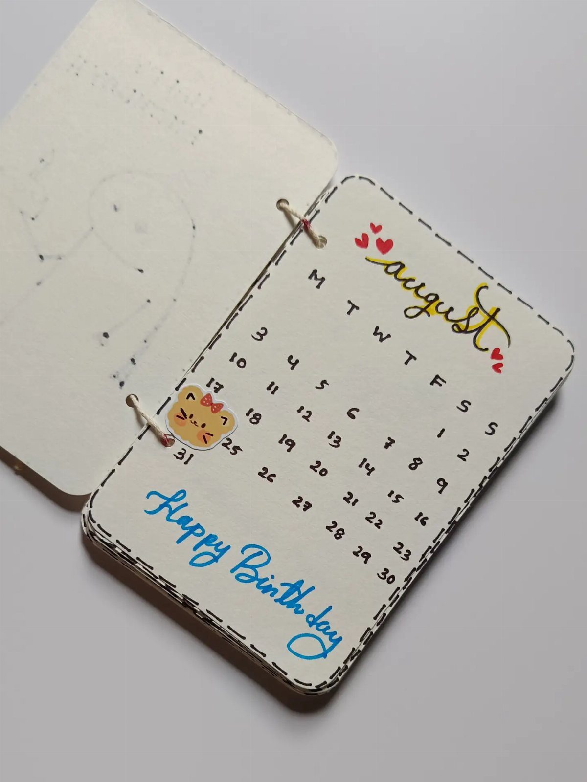 Handmade August birthday calendar with a cute cat and blue cursive lettering.
