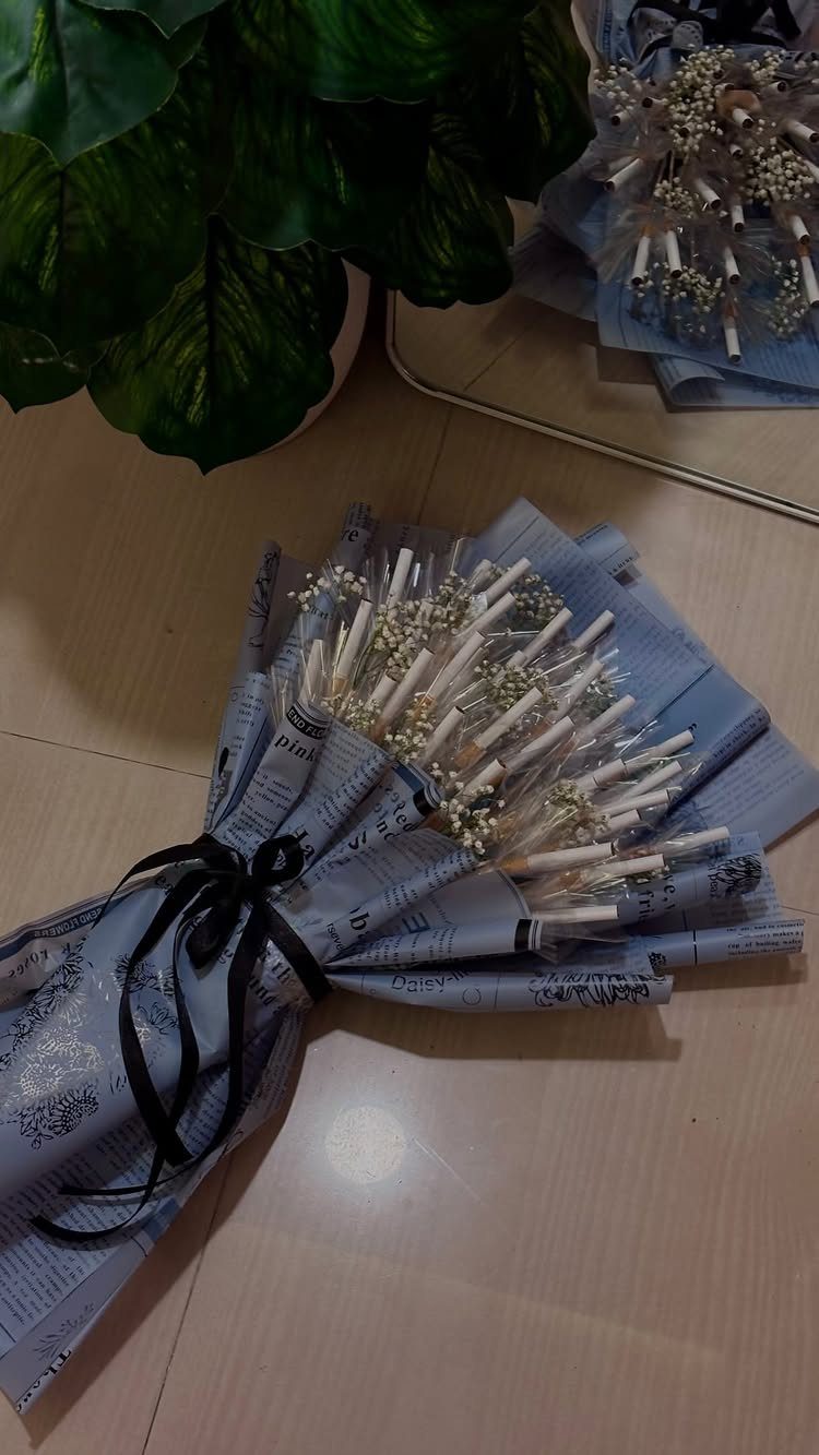 Paper scroll bouquet wrapped in blue paper with a black ribbon and white flowers.