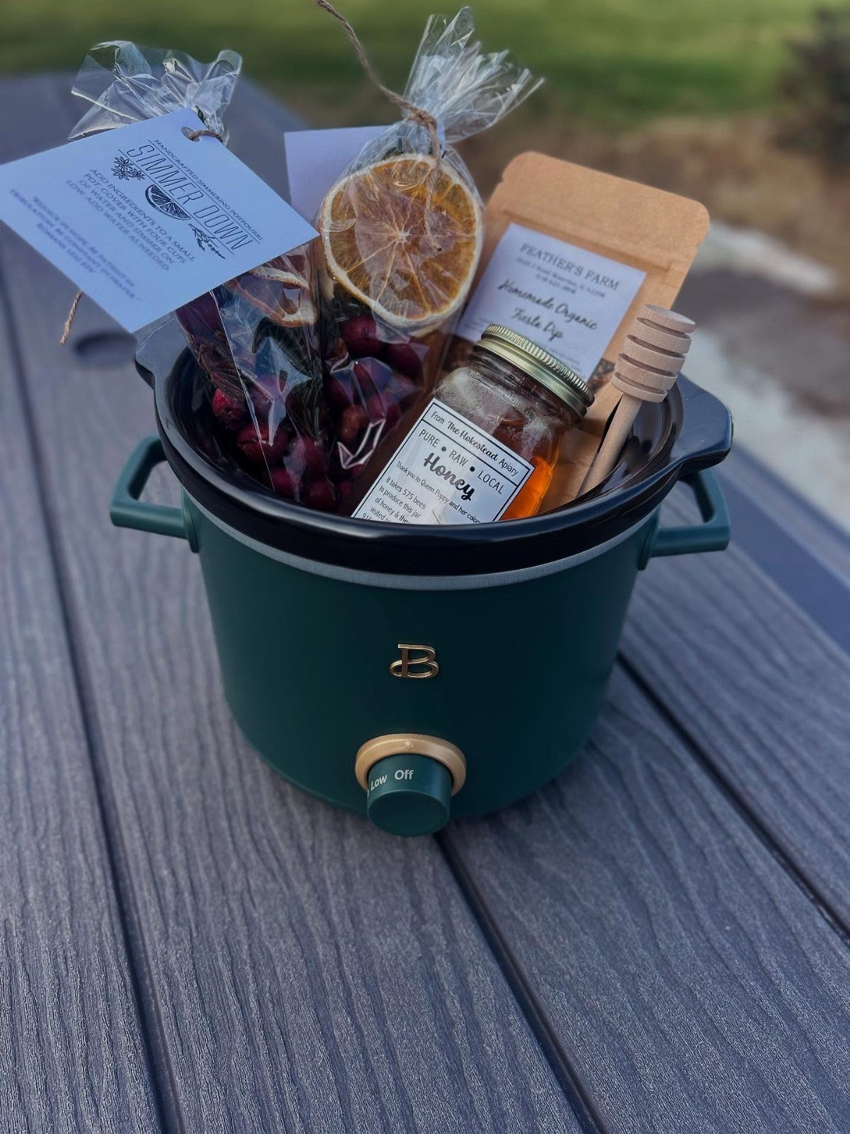 Green slow cooker filled with honey, dried fruit, and gourmet treats as a gift.
