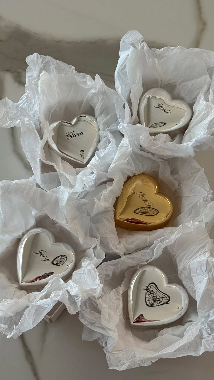 Heart-shaped ceramic trinket dishes with custom names resting in white tissue paper.