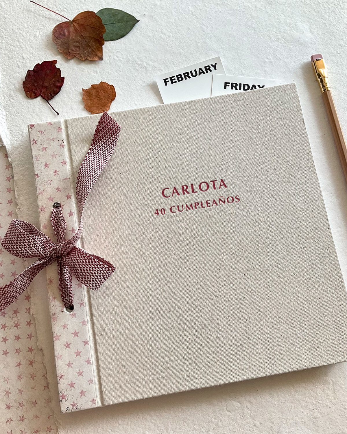 Linen photo album for Carlota's 40th birthday with a burgundy ribbon bow.
