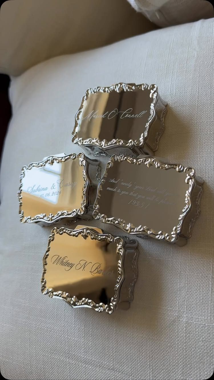 Four small silver engraved jewelry boxes with ornate edges on white fabric