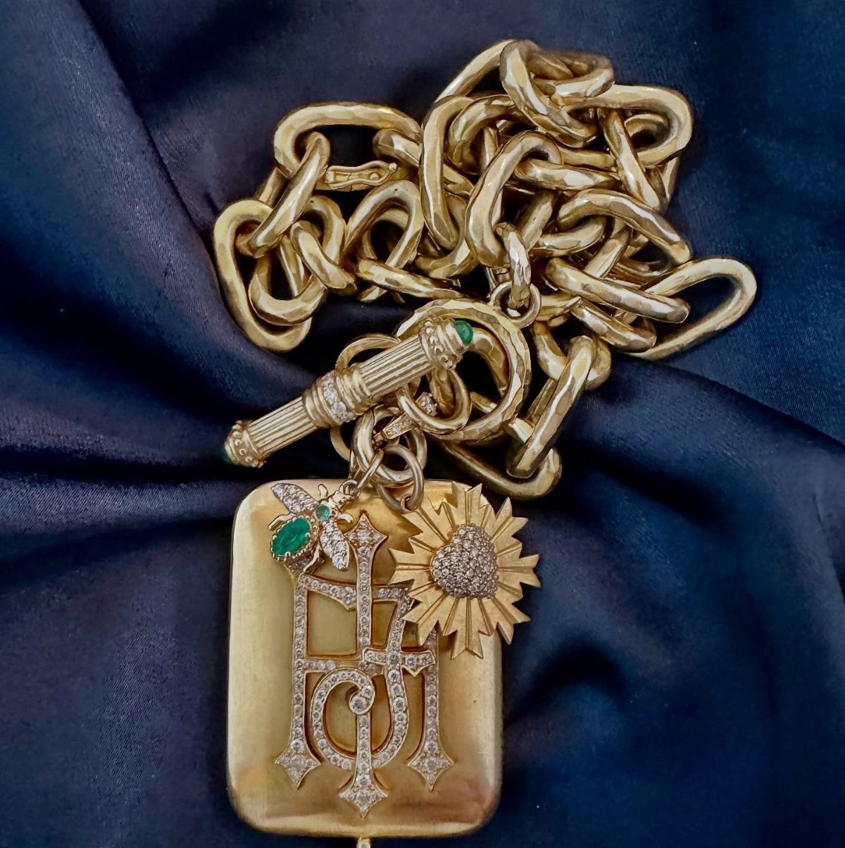 Gold chain necklace with a diamond monogram pendant and sunburst heart charm.