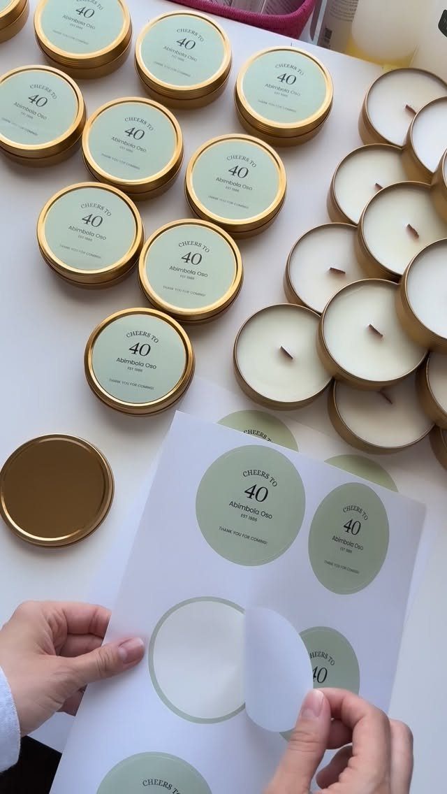 Gold tin candles with light green labels reading Cheers to 40 being prepared.