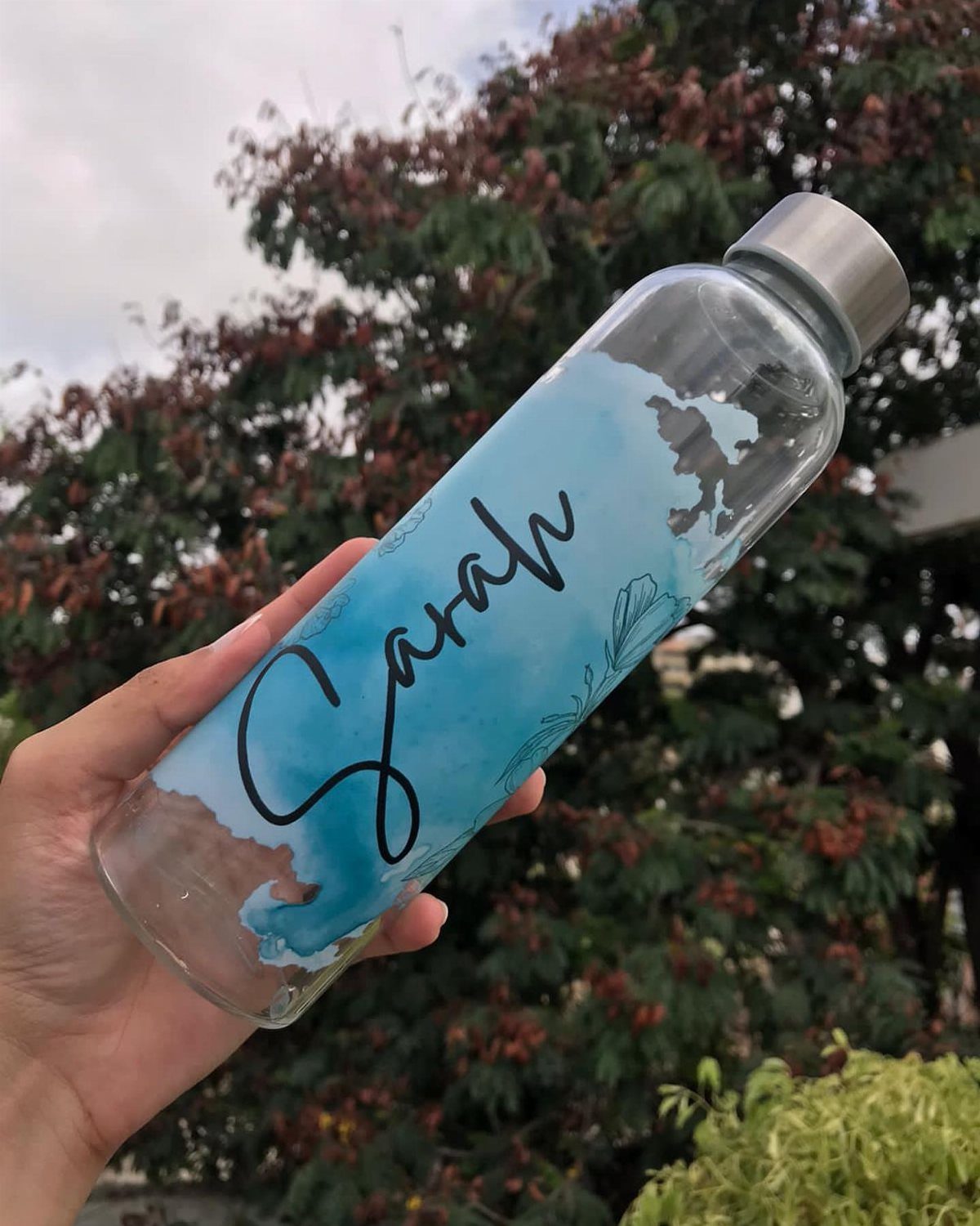 Glass water bottle with blue watercolor design and the name Sarah in cursive.