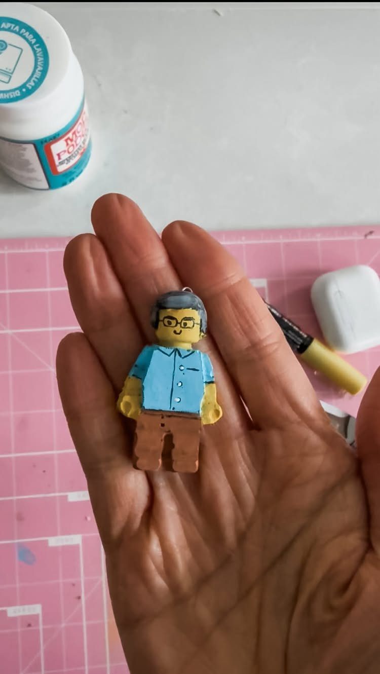 Handmade clay figurine of a man held in a person's open palm.