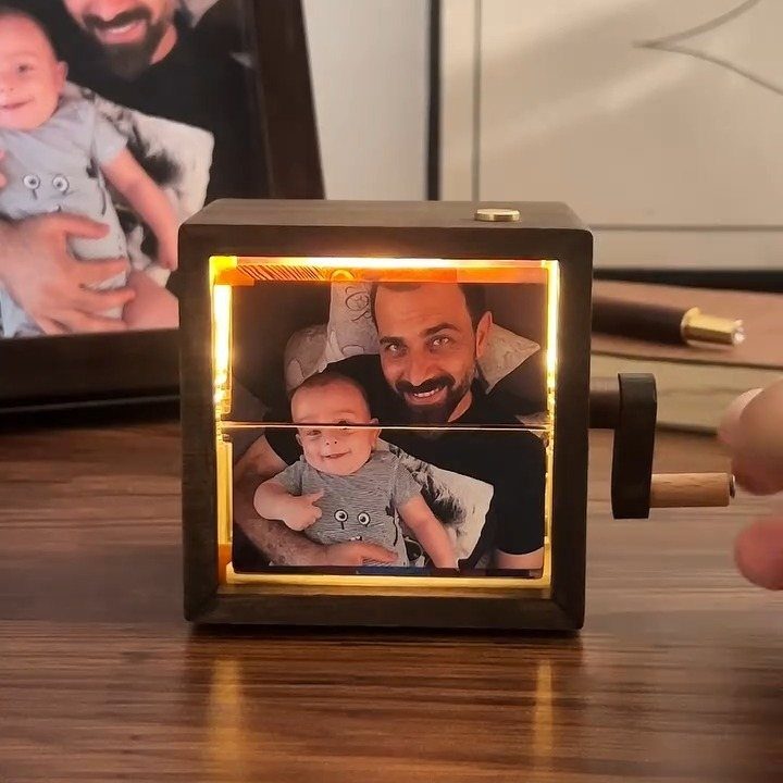 Wooden photo cube displaying a backlit picture of a father and baby boy.