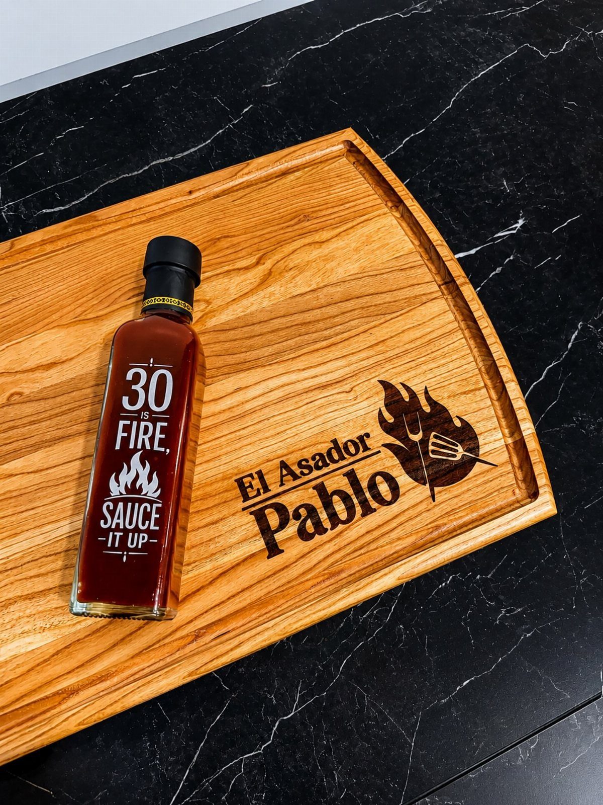 Engraved wooden tray and custom sauce bottle on a black marble countertop