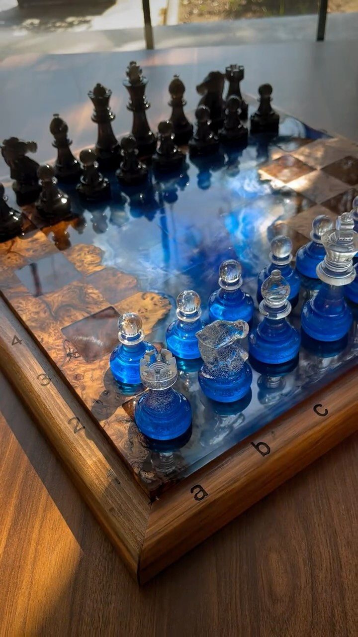 Handmade chess set with blue resin board and translucent blue and black pieces.