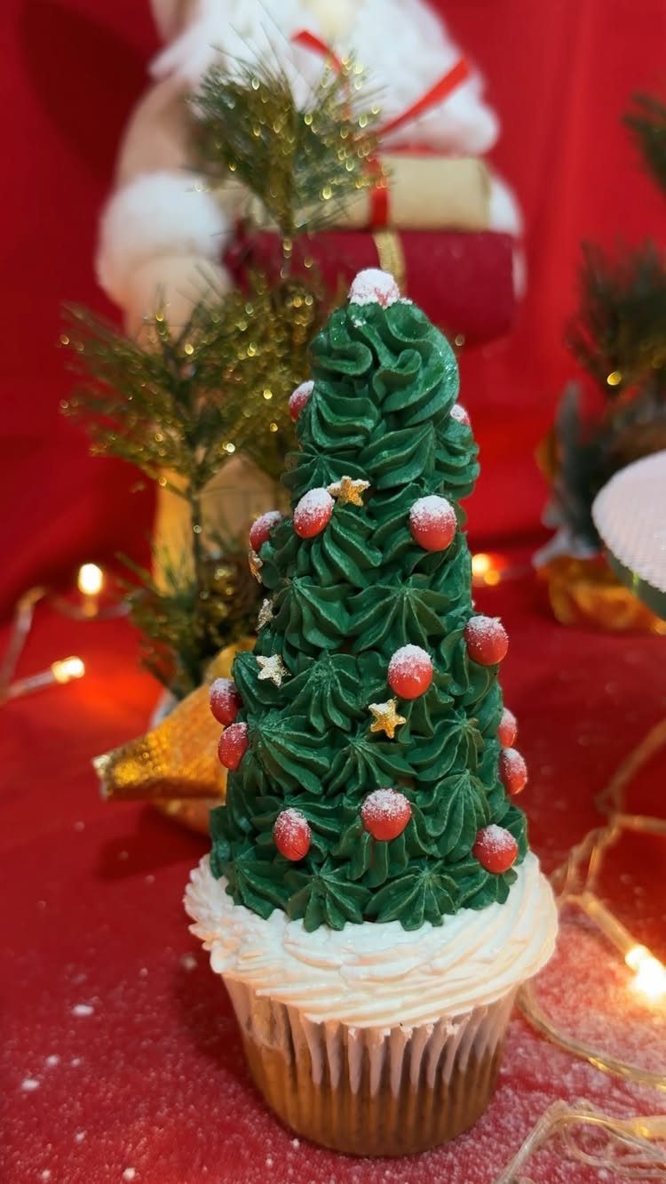 Christmas tree cupcake with green frosting and red sprinkles on a red background