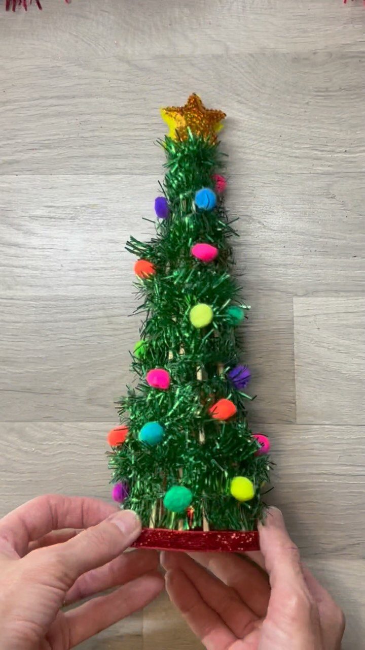 Handmade tinsel Christmas tree decorated with colorful pom-poms and a gold star topper.