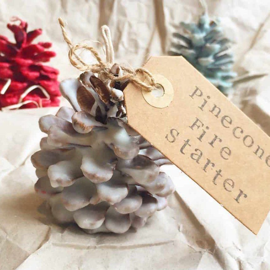 Wax-dipped pinecone fire starter with a brown cardboard tag on white paper.