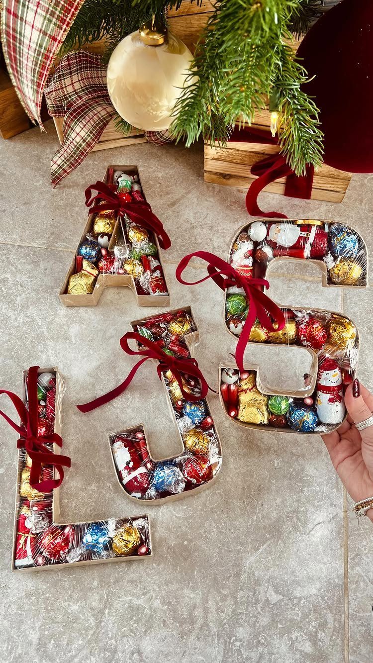 Letter-shaped containers filled with colorful wrapped chocolates tied with red ribbons.