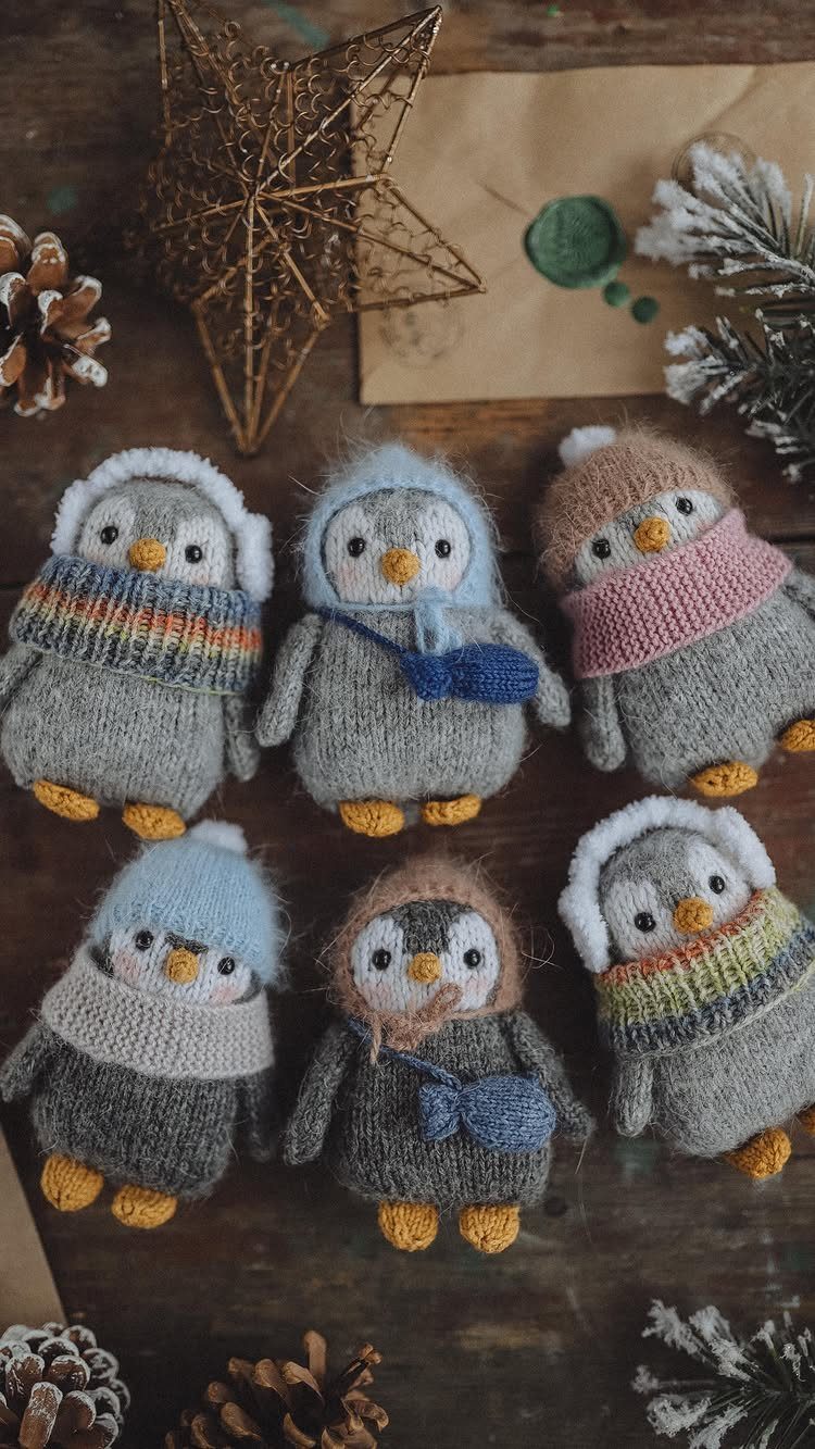 Six knitted penguin figurines with colorful scarves on a rustic wooden background.