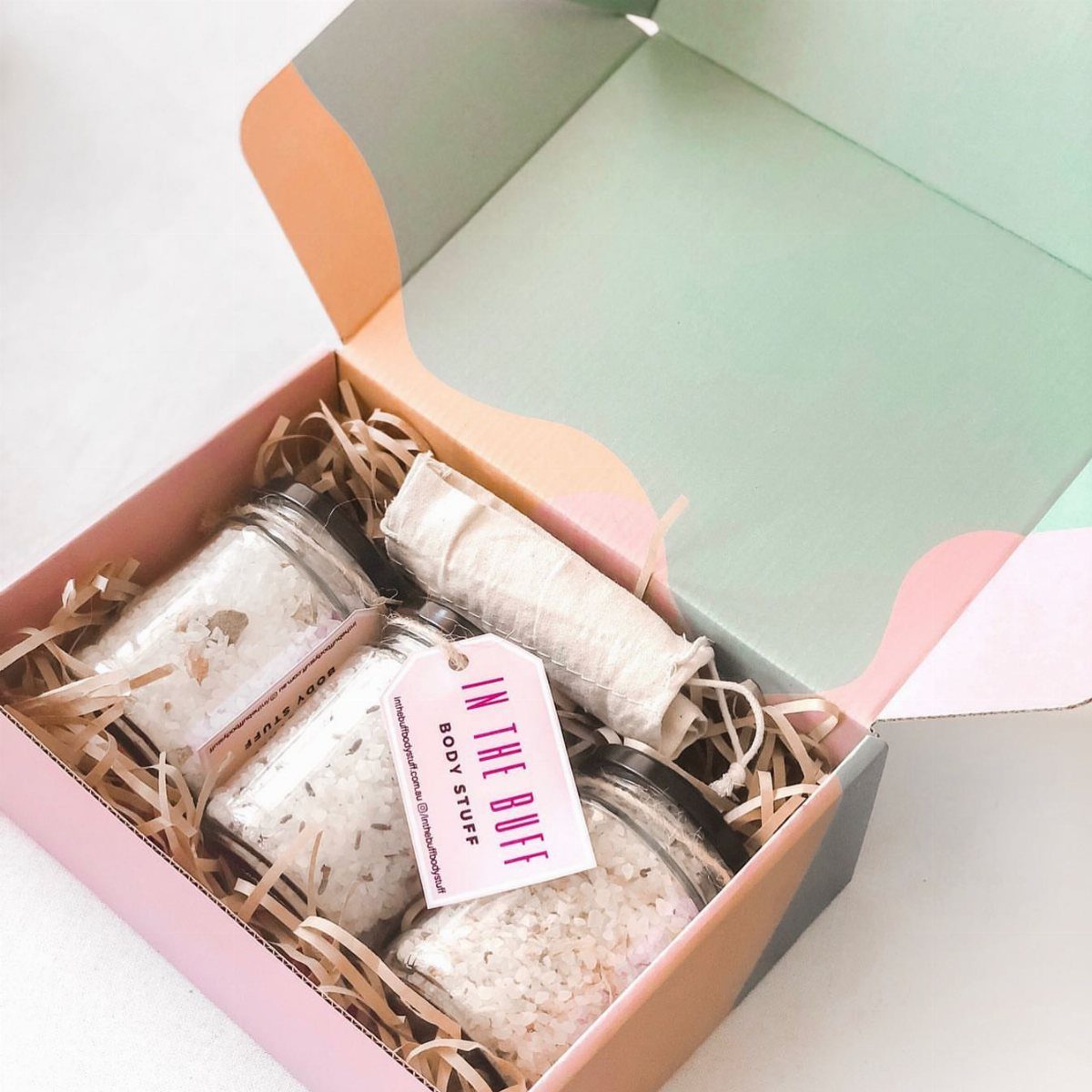 Three jars of white bath salts and a cloth wrap in a gift box.