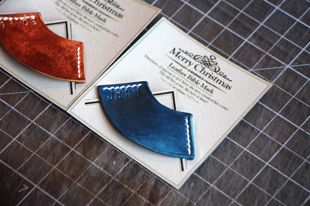 Blue and brown leather bookmarks with white stitching on Christmas gift cards.