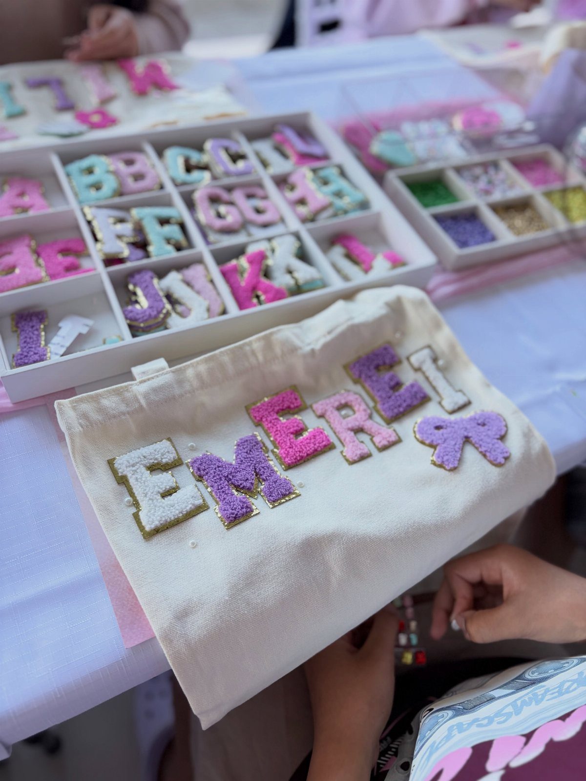 Canvas tote bag decorated with colorful glittery letters spelling the name Emerei.