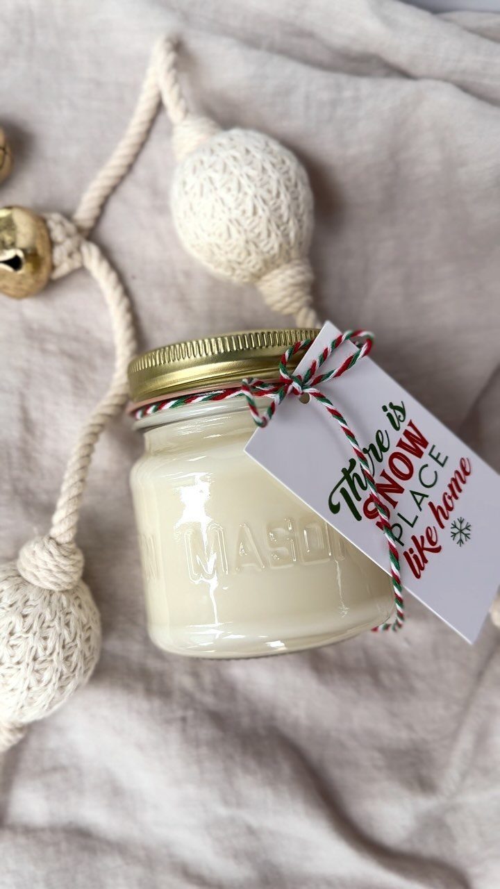 White wax candle in a mason jar with a gold lid and gift tag.