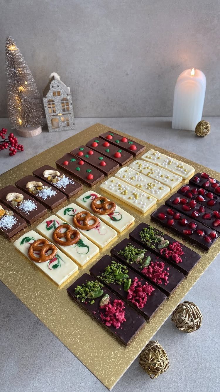 Assorted decorated chocolate bars on a gold tray with Christmas decorations in background.
