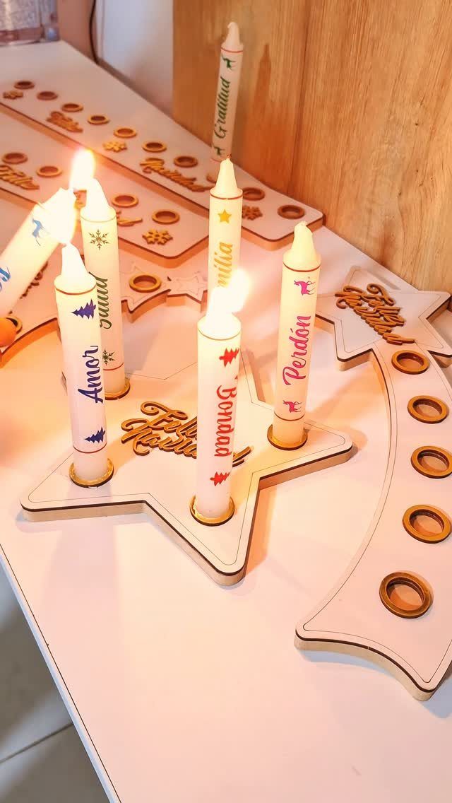 Star-shaped wooden candle holders with decorated white taper candles on a white table.