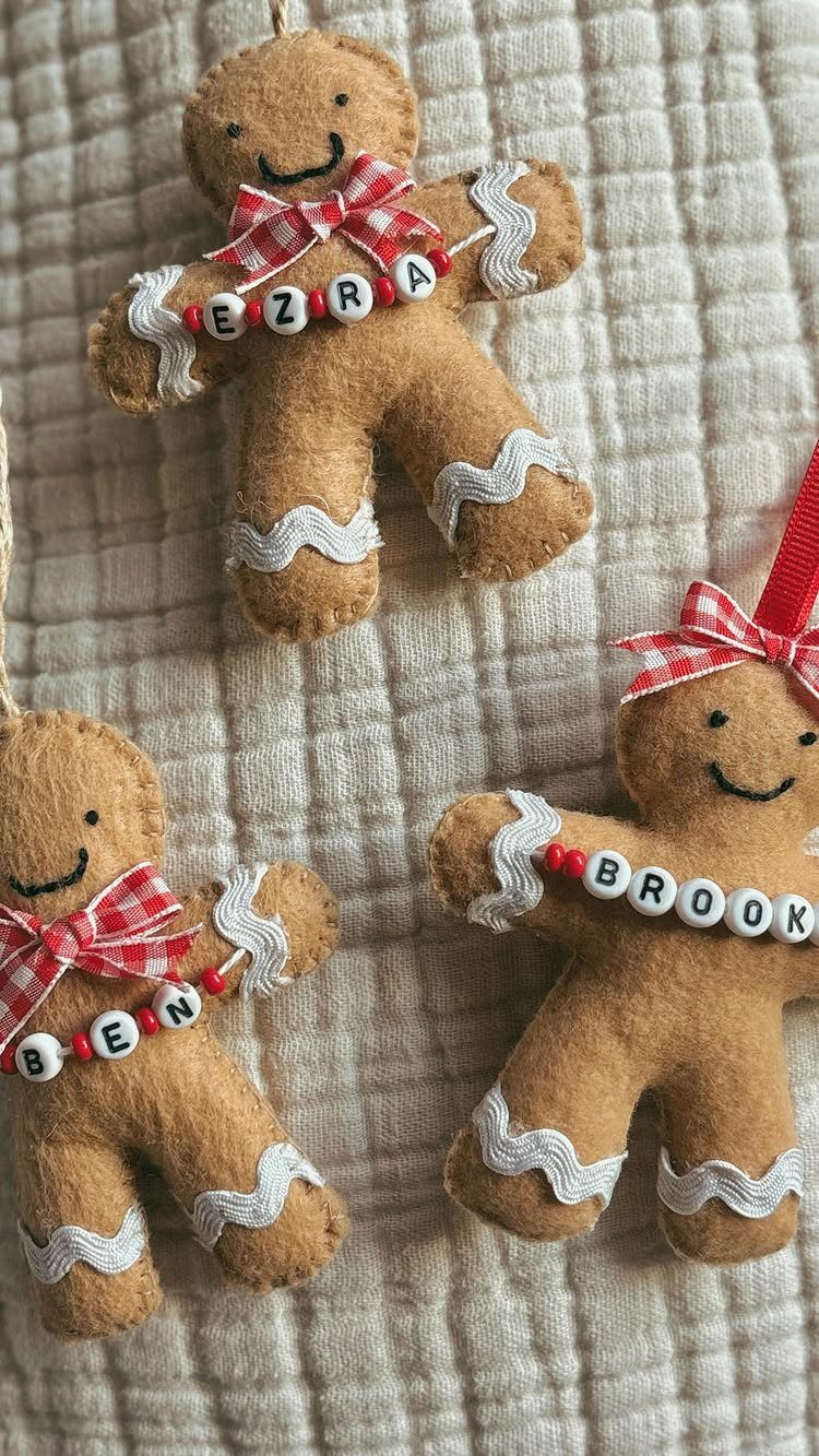 Three personalized felt gingerbread man ornaments with name beads on white fabric.