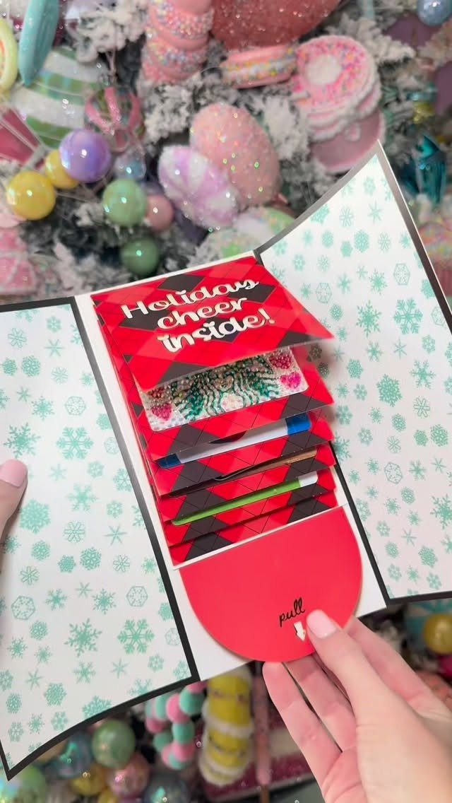 Red holiday card with a pull-tab mechanism holding several gift cards and a pen.