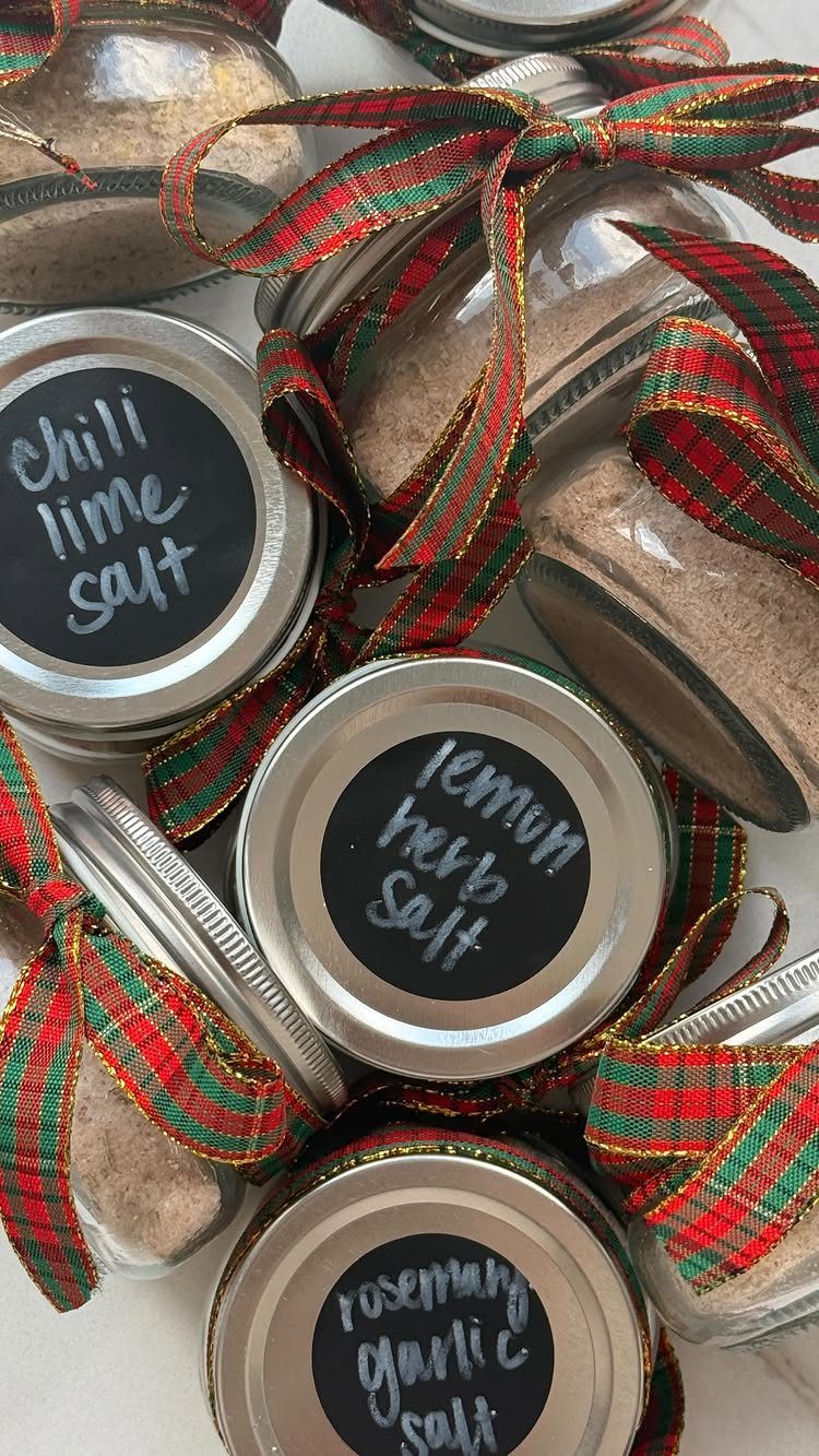 Glass jars of flavored salts with plaid ribbons and handwritten labels for gifts.