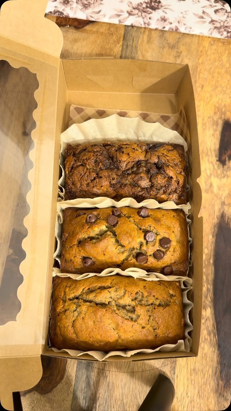 Three mini quick bread loaves in a brown cardboard gift box on wood.