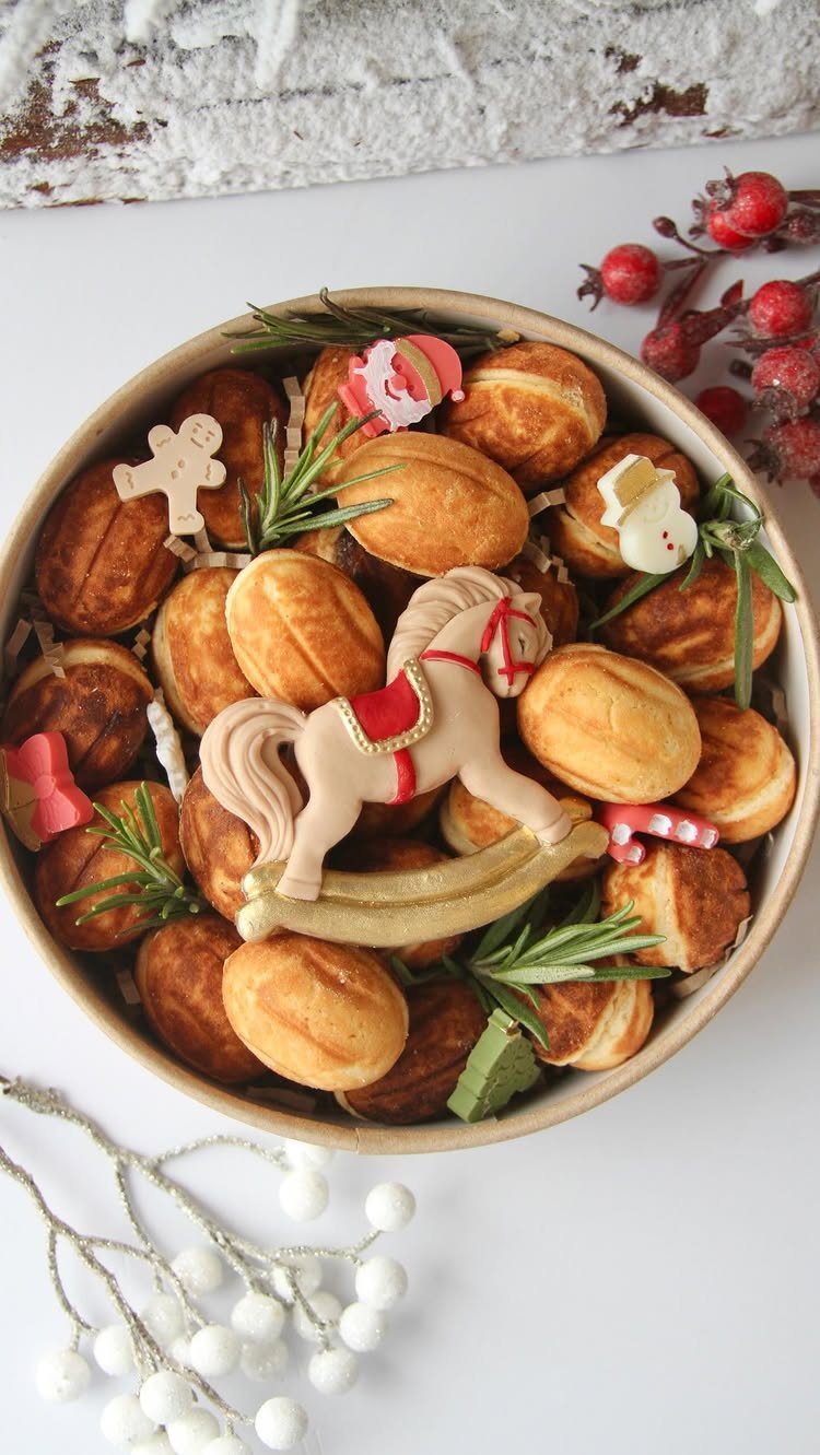 Baked cookies in a round box decorated with icing figures and rosemary sprigs.