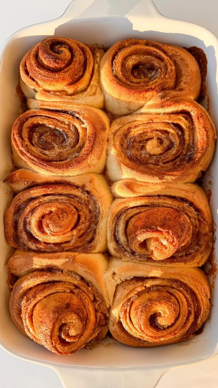 Cinnamon rolls baked in a white rectangular dish, viewed from above.