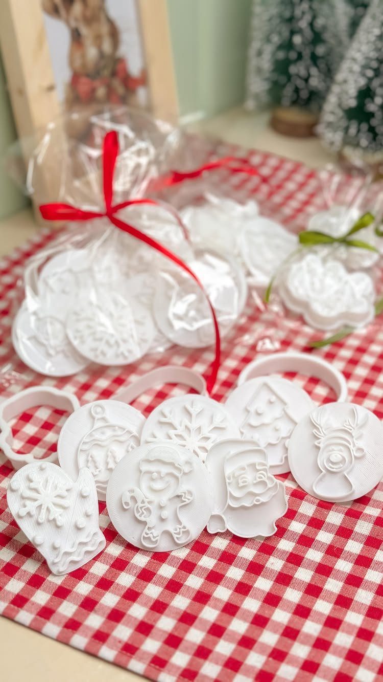White Christmas cookie cutters on a red and white checkered tablecloth with ribbons.