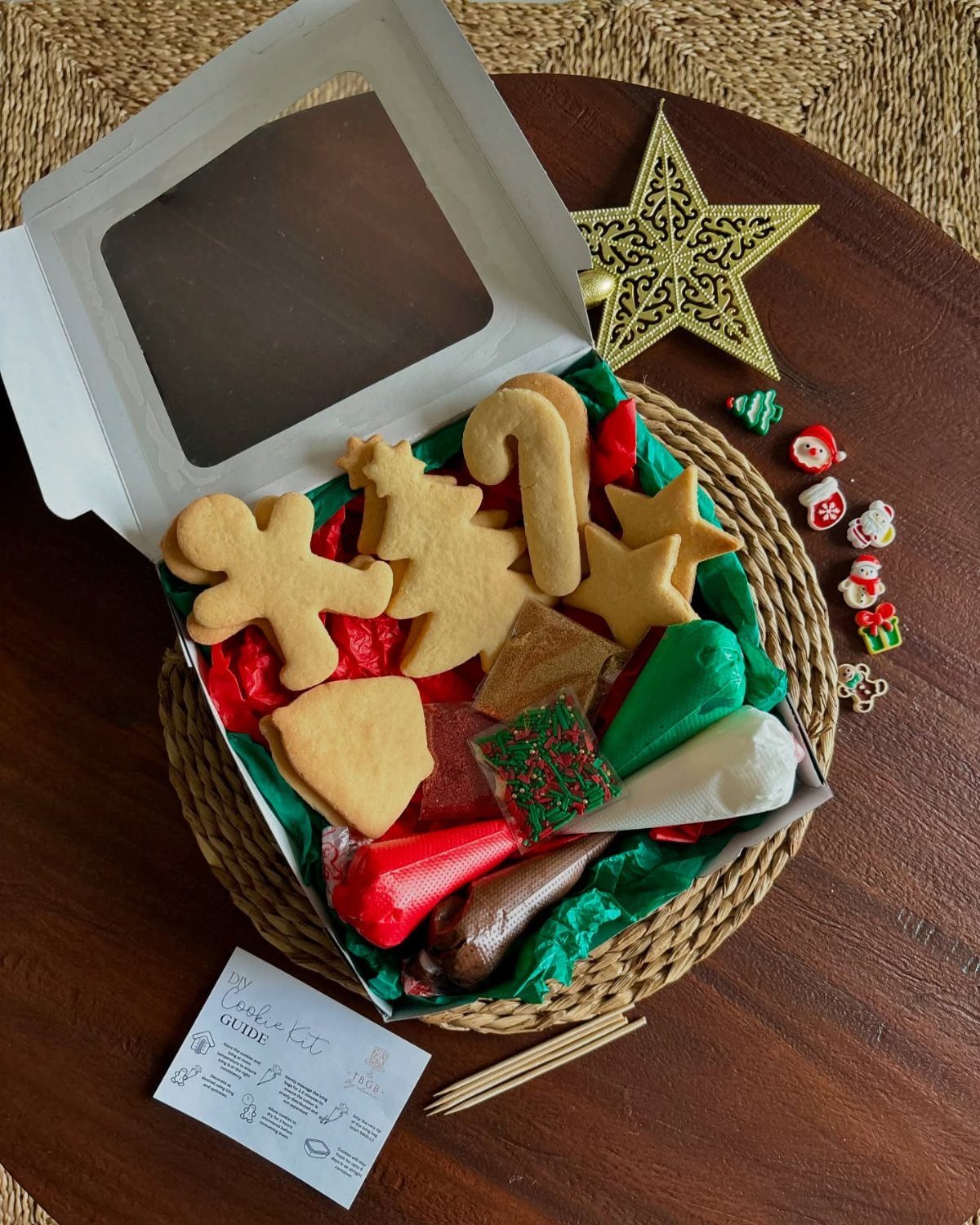 Cookie decorating kit with gingerbread cookies, colorful icing piping bags, and sprinkles.