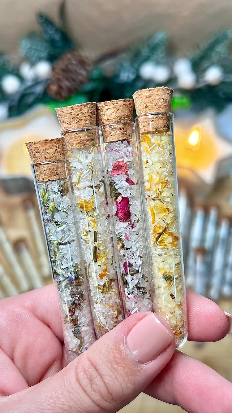 Four glass test tubes filled with herbal bath salts and dried flower petals.