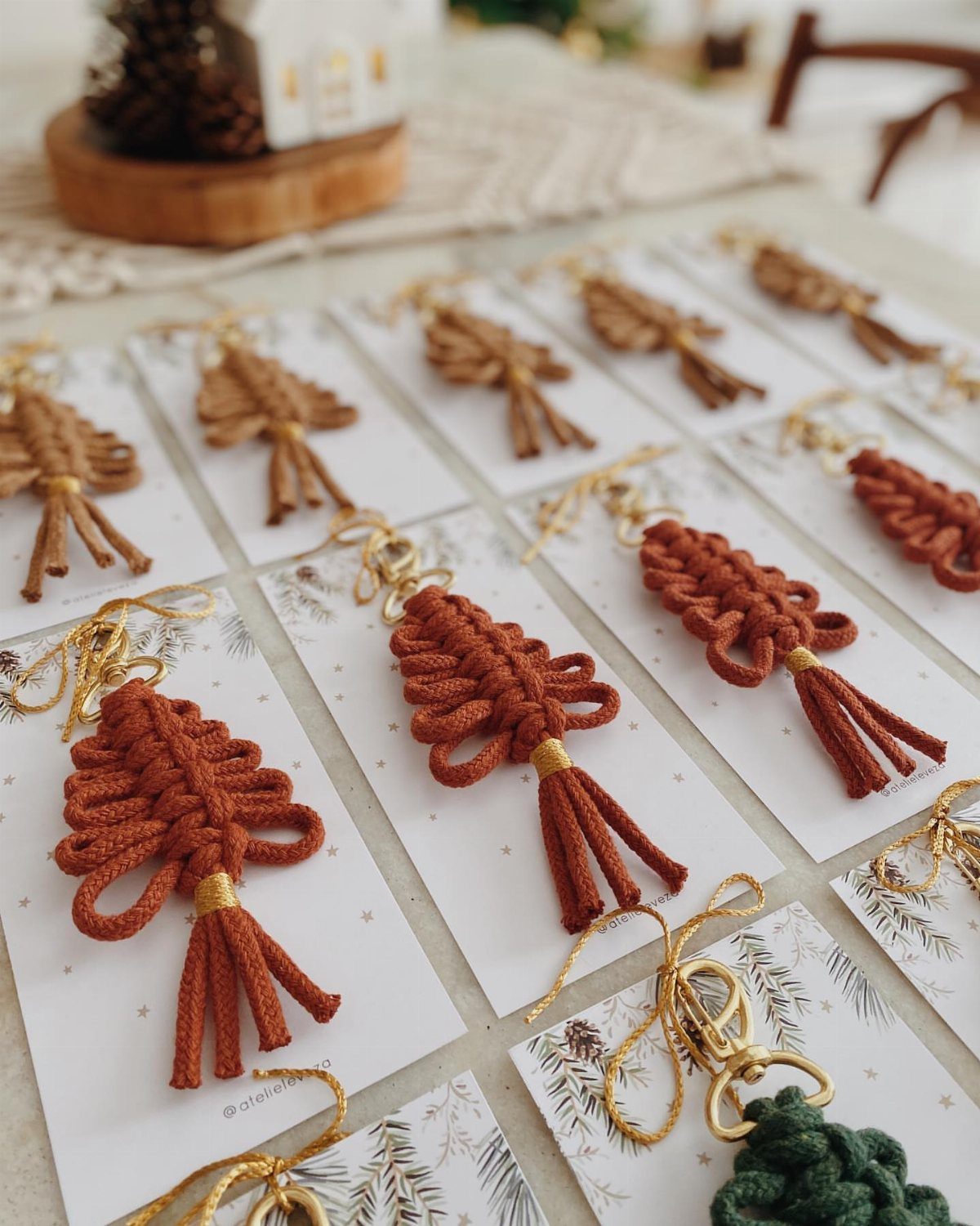 Macrame keychains in earthy tones attached to decorative white cards on a table.