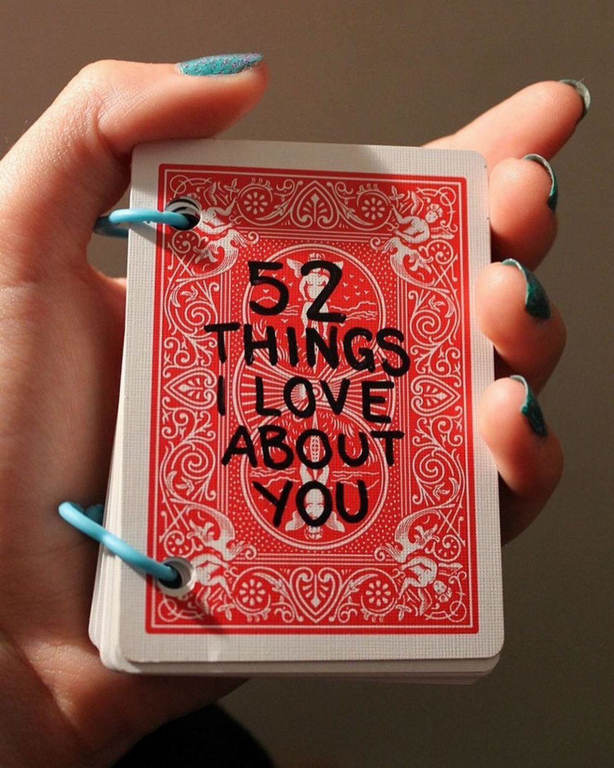 Hand holding a red and white deck of cards titled 52 Things I Love About You