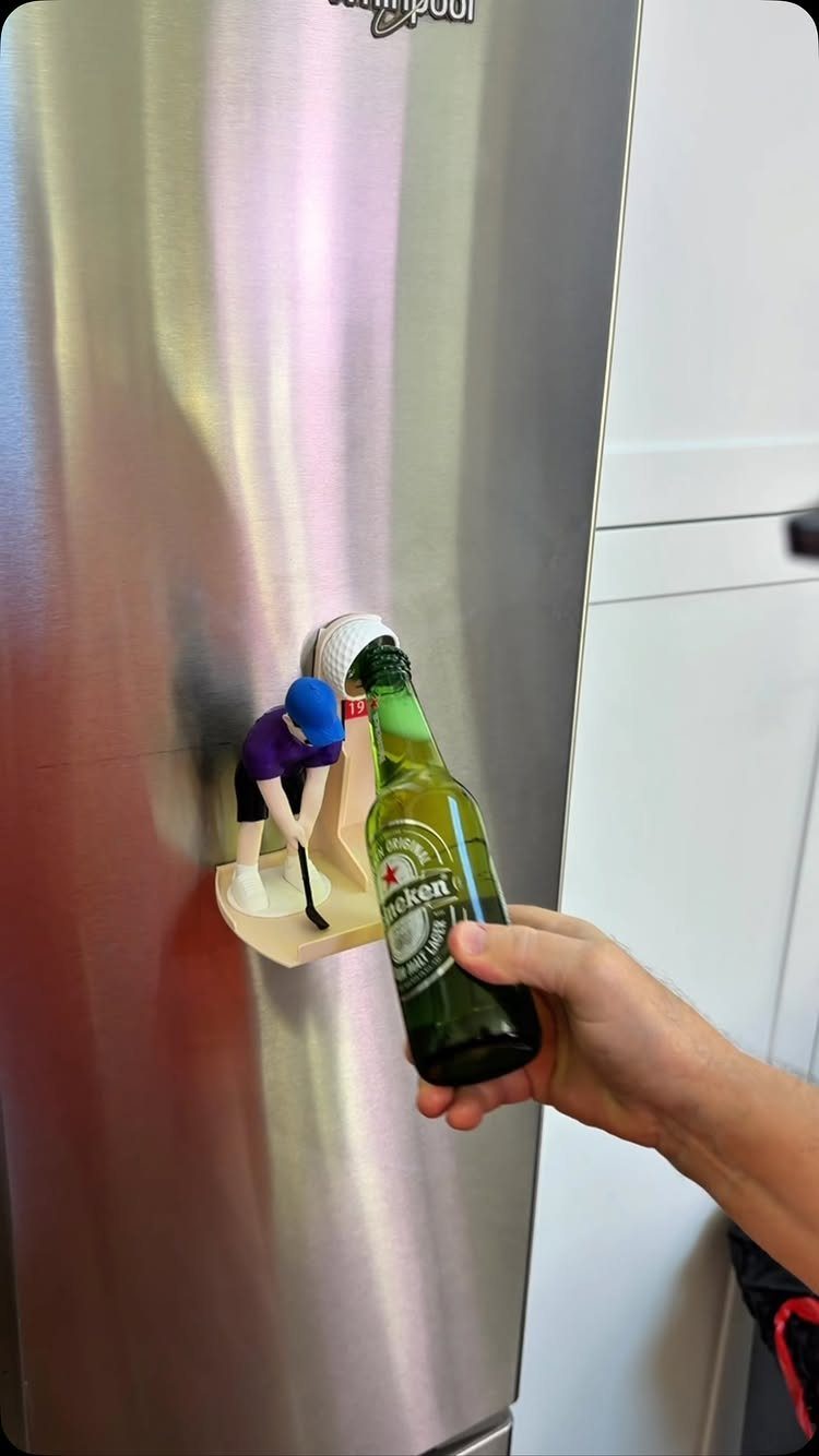 Hand opening a beer bottle using a hockey player themed wall-mounted bottle opener.