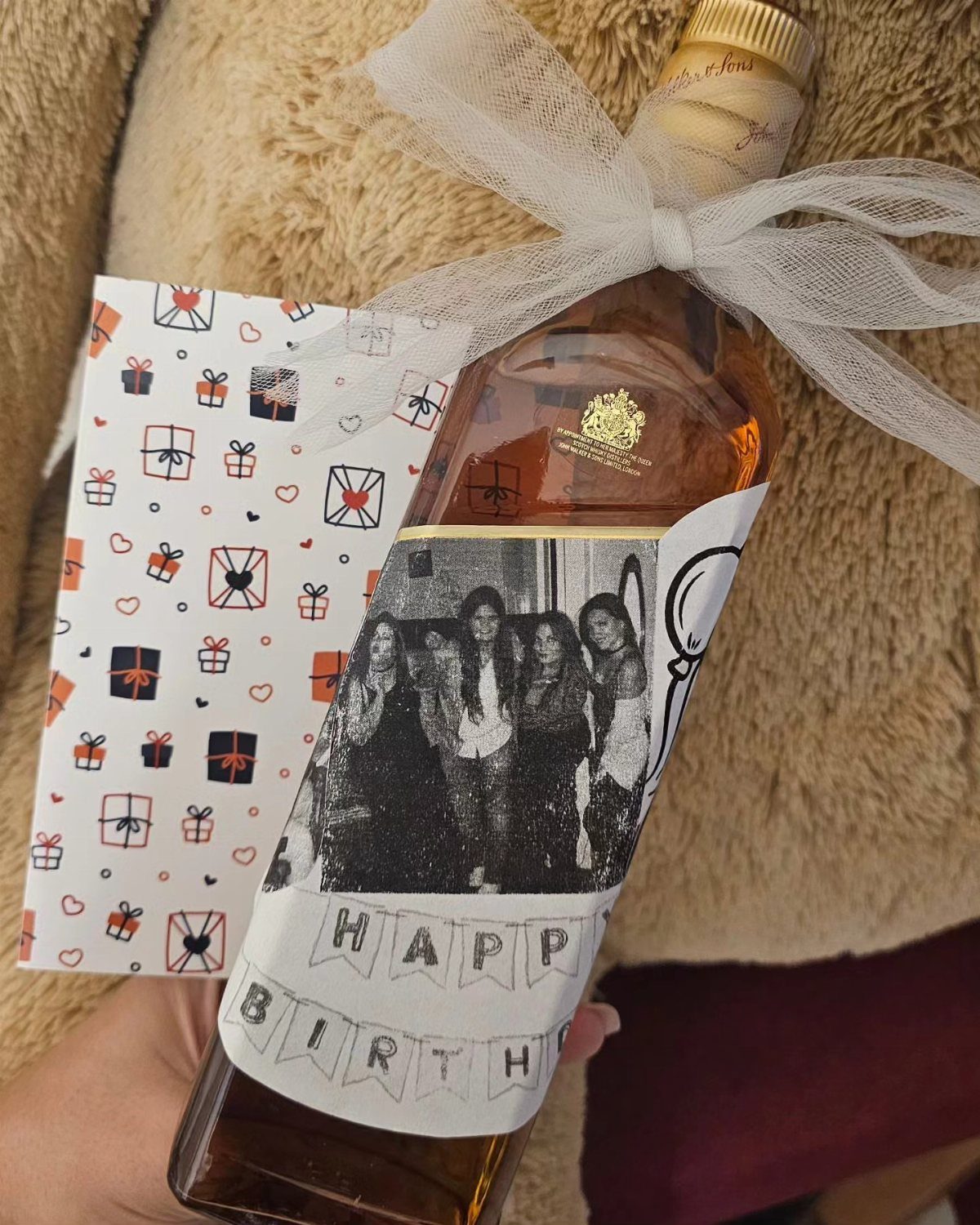 Bottle of liquor with a custom birthday label featuring a group photo and bow.