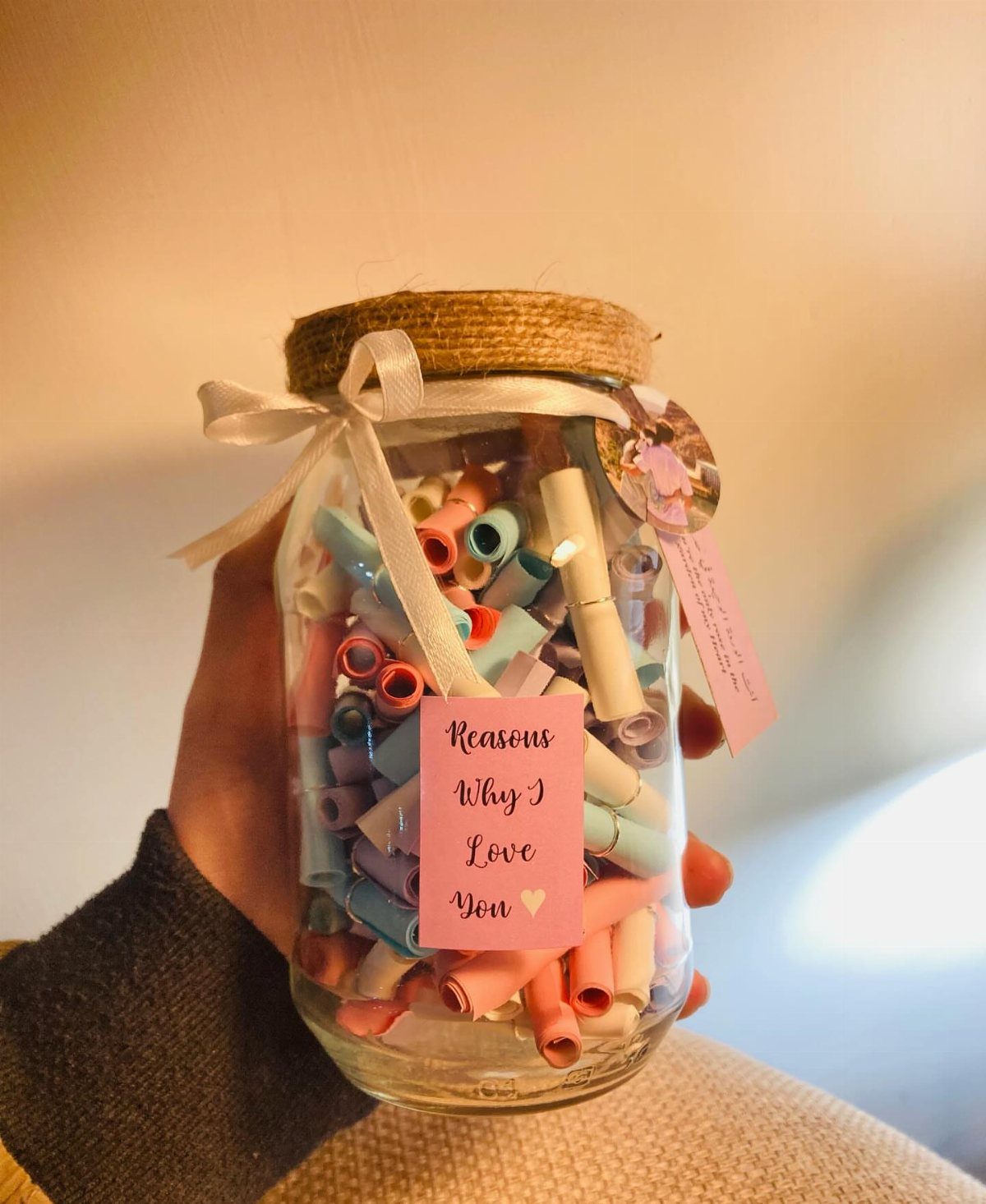 Mason jar filled with colorful rolled paper notes and a love label.
