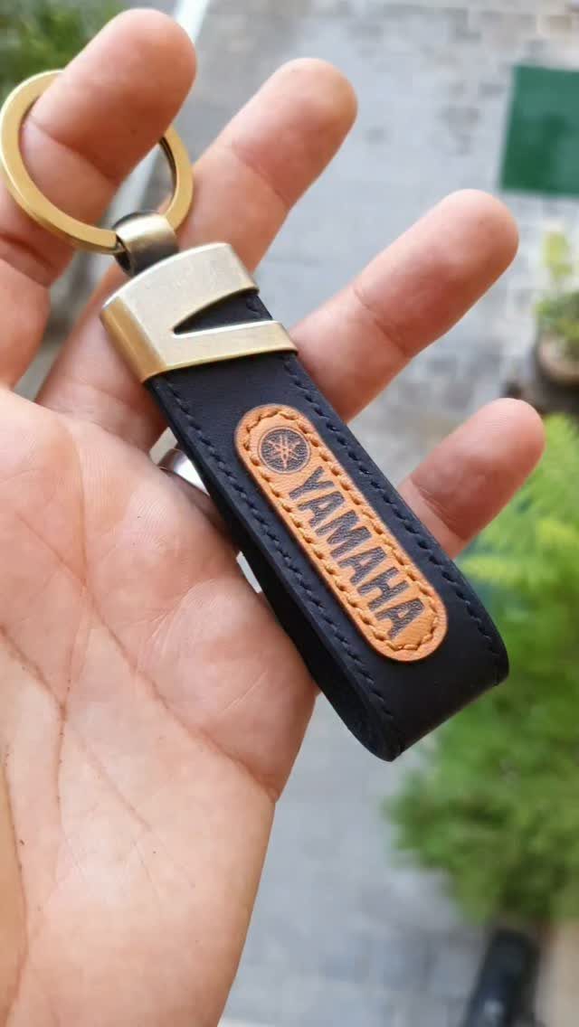 Black leather Yamaha keychain with gold metal ring held in a person's hand.