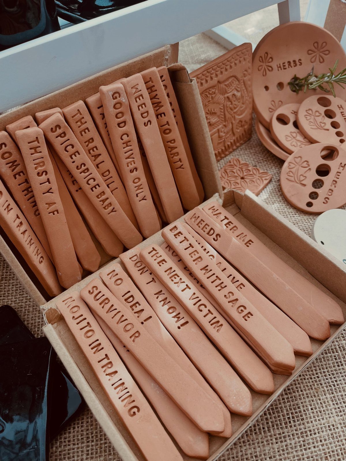 Terracotta clay plant markers with stamped text arranged in a cardboard box
