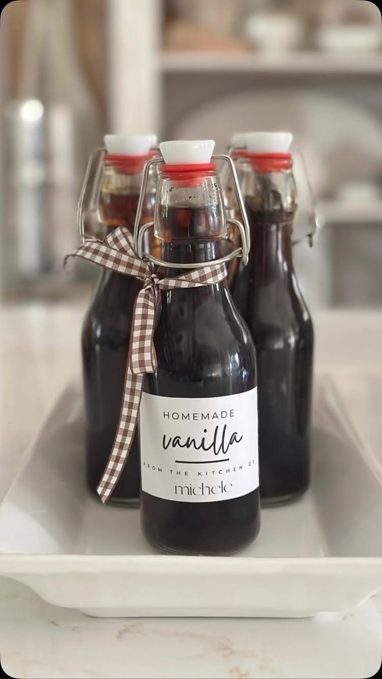 Three bottles of homemade vanilla extract with checkered ribbons on a white tray