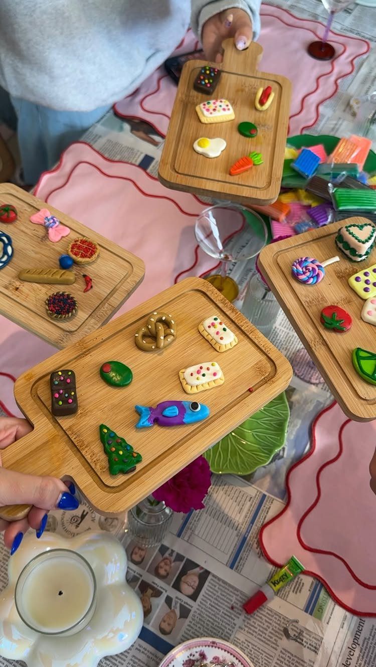 Miniature clay food figures arranged on small wooden boards on a craft table