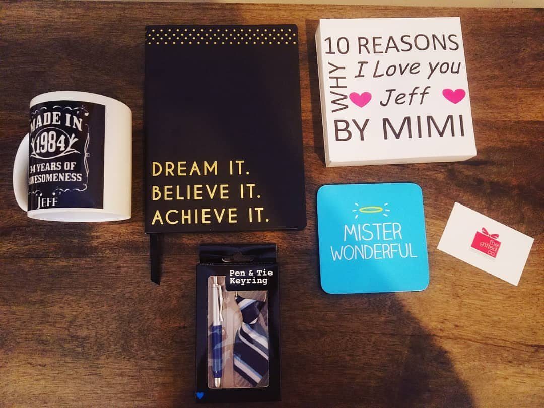 Customized white mug and various personalized gifts arranged on a dark wooden table.