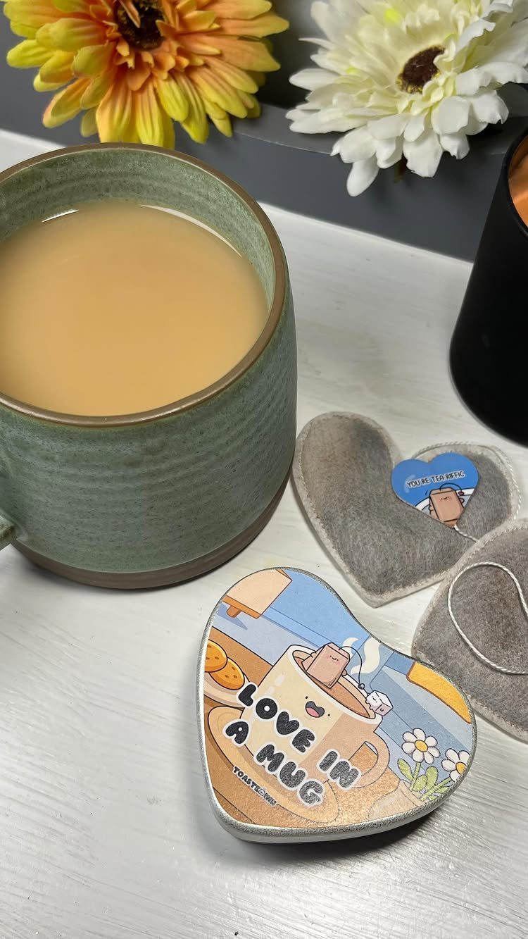 Heart-shaped tea bags and a mug of tea with flowers in the background.