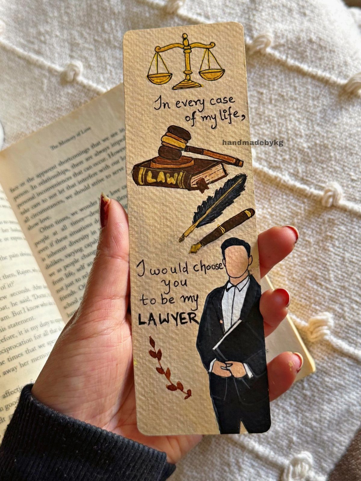 Handmade law-themed bookmark with romantic text and illustrations held over an open book