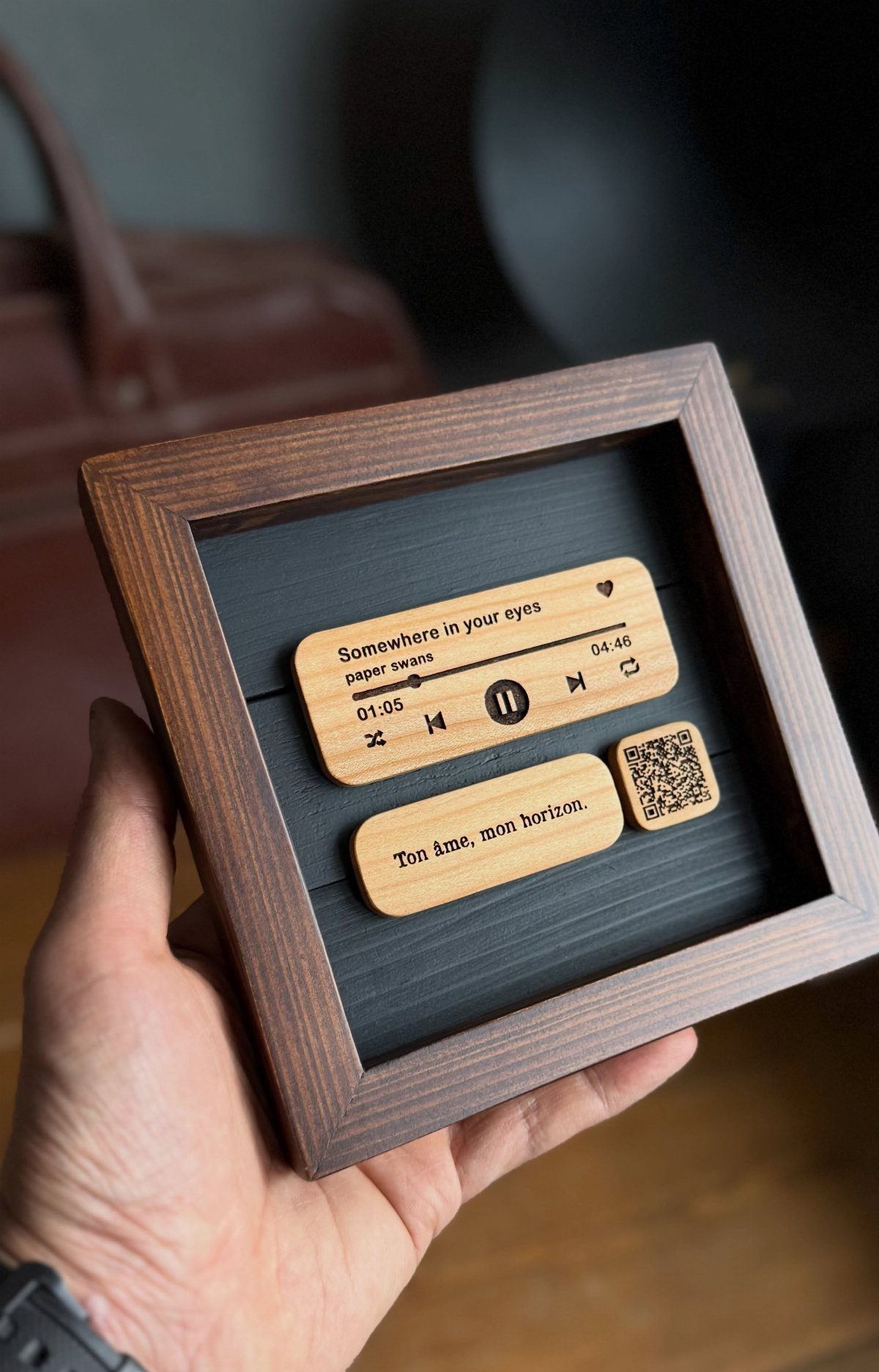 Wooden music player plaque in a shadow box held by a hand