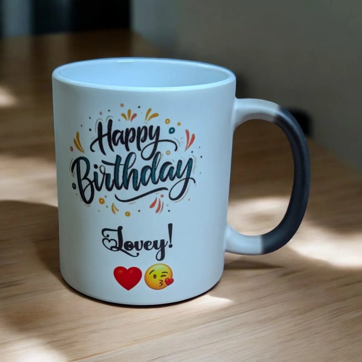White ceramic mug with Happy Birthday Lovey text and emojis on wooden table