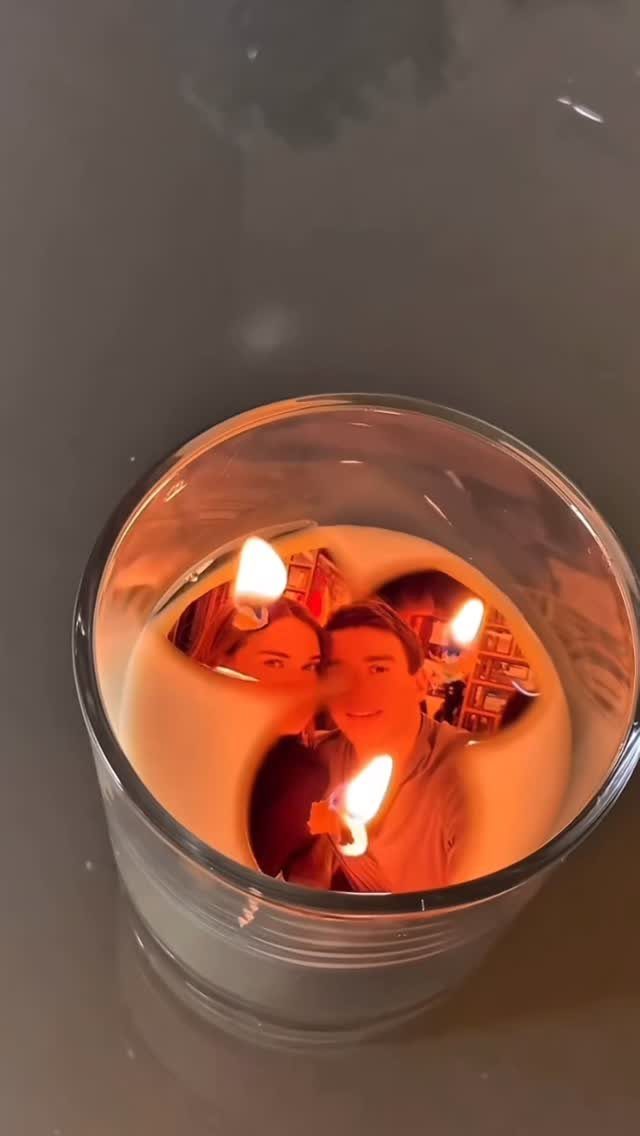 White candle in a glass jar with a photo of a couple embedded inside.