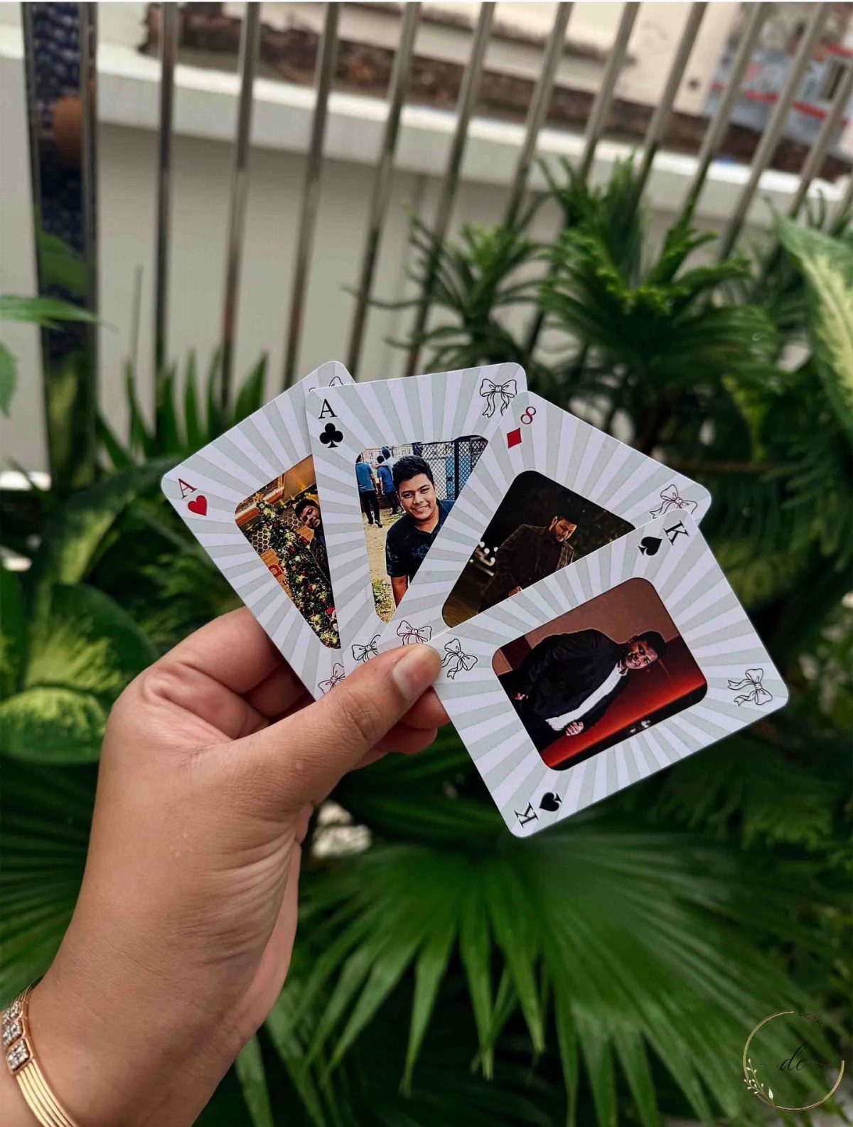 Hand holding custom playing cards featuring personal photographs of a man outdoors.